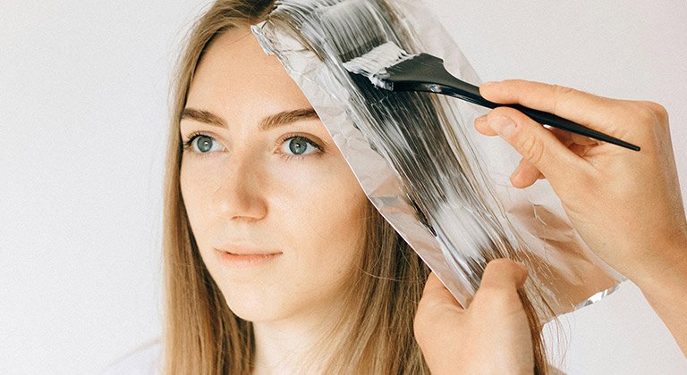 Dunkelblonde Frau, der die Haare gesträhnt werden