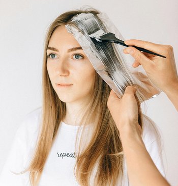 Dunkelblonde Frau, der die Haare gesträhnt werden