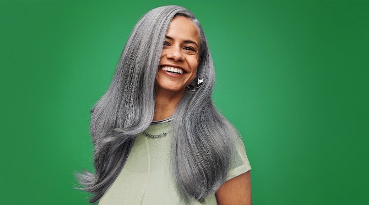 Lächelnde Frau mit grauen Haaren vor einem grünen Hintergrund
