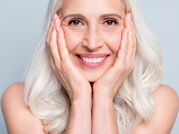 Bild einer Frau mit platinblonden Haaren, die ihr Gesicht in ihre Handflächen stützt
