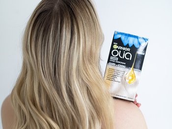 Blonde Frau von hinten, die den Olia Toner auf ihre Schulter lehnt