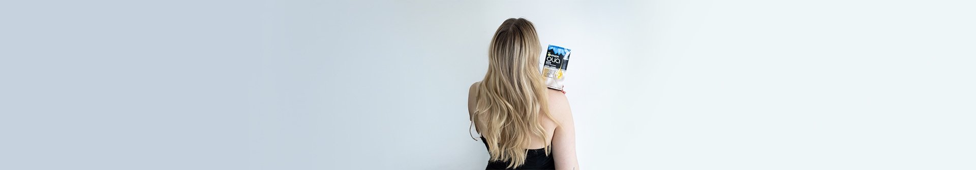 Rückansicht einer Frau mit langen silbernen/grauen Haaren, die eine Nuance von Garnier Olia hält