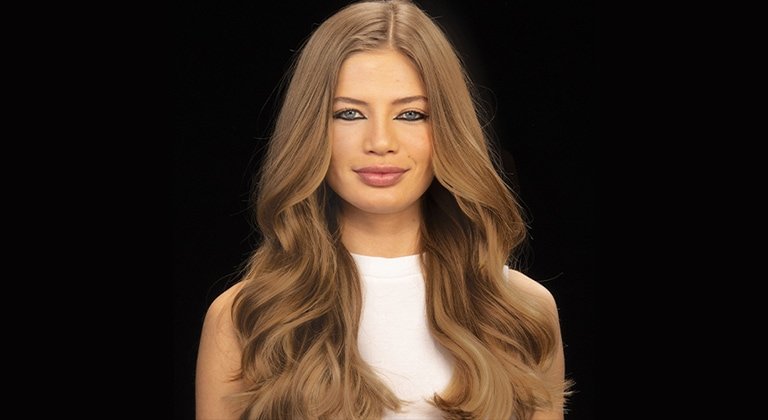 Junge Frau mit langen dunkelblond gefärbten Haaren vor schwarzem Grund