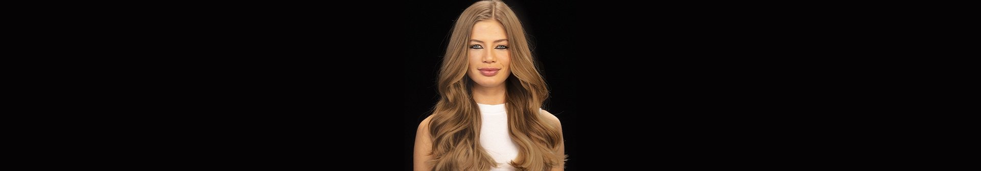 Junge Frau mit langen dunkelblond gefärbten Haaren vor schwarzem Grund