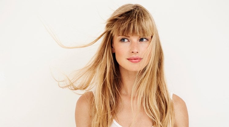 Frau mit langen, mittelblonden Haaren, die leicht im Wind wehen
