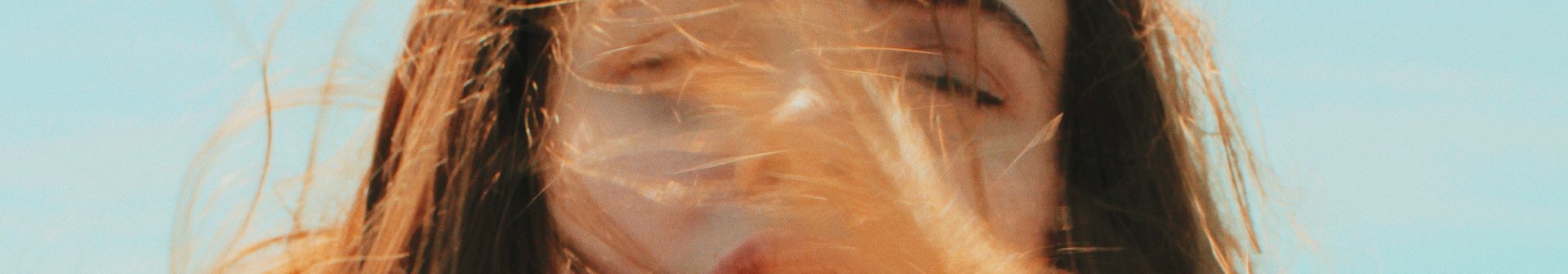 Wind weht einer Frau ihr rotbraunes Haar ins Gesicht