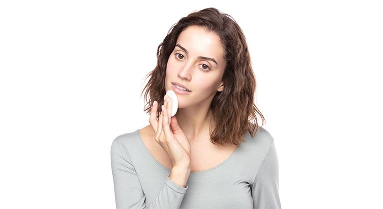 Frau streicht sich mit einem pad über ihr Kinn.