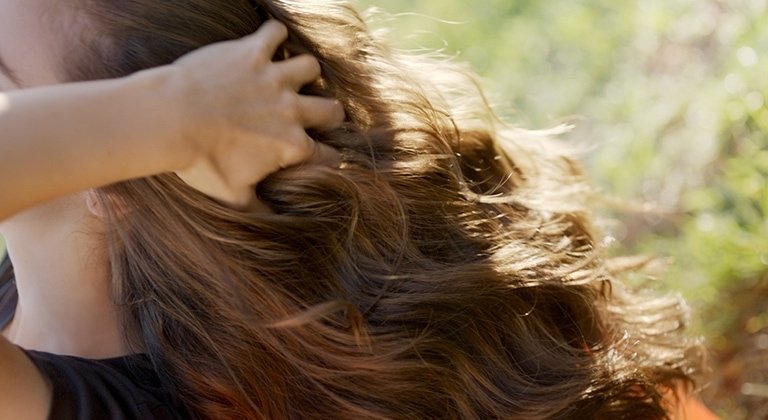 Frau fässt sich ins volle Haar