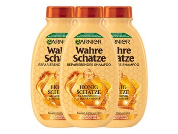 Wahre Schätze Reparierendes Shampoo Honig Schätze in der Hand einer Frau vor einem orangebraunen Hintergrund