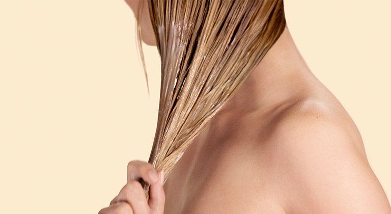 Eine Frau fasst ihre langen blonden nassen Haare zusammen