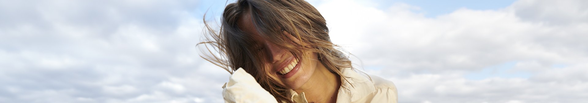 Eine lächelnde junge Frau wehen die Haare vor ihr Gesicht