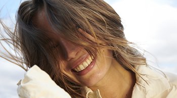 Eine lächelnde junge Frau wehen die Haare vor ihr Gesicht