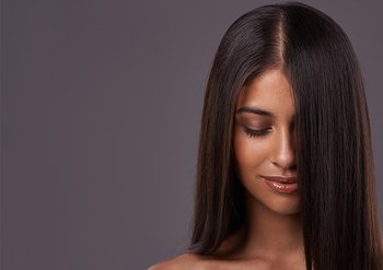 Frau mit langen dunklen Haaren, die nach unten schaut und lächelt