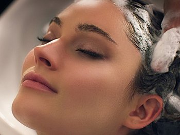 Dunkelhaare Frau, die die Haare gewaschen bekommt