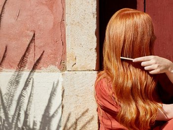 Rothaarige Frau von der Seite, die ihre langen Haare kämmt
