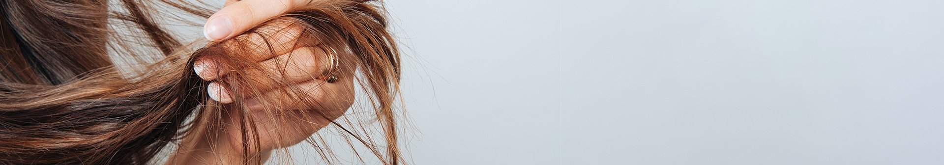 Frau hält Haare zwischen den Fingern