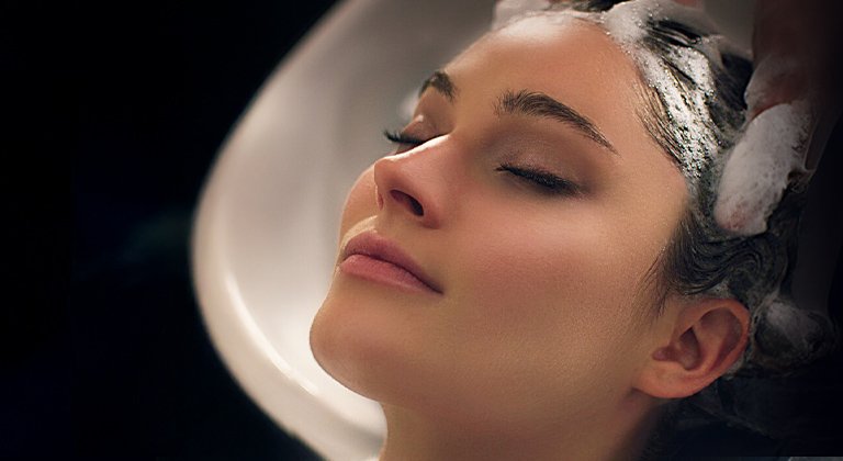 Brünette Frau bekommt beim Friseur die Haare gewaschen