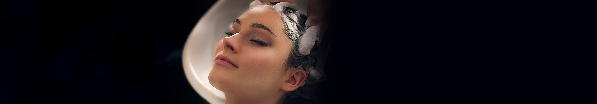 Brünette Frau bekommt beim Friseur die Haare gewaschen