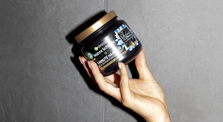 Eine Hand hält Garnier Wahre Schätze Ausgleichende Haarmaske