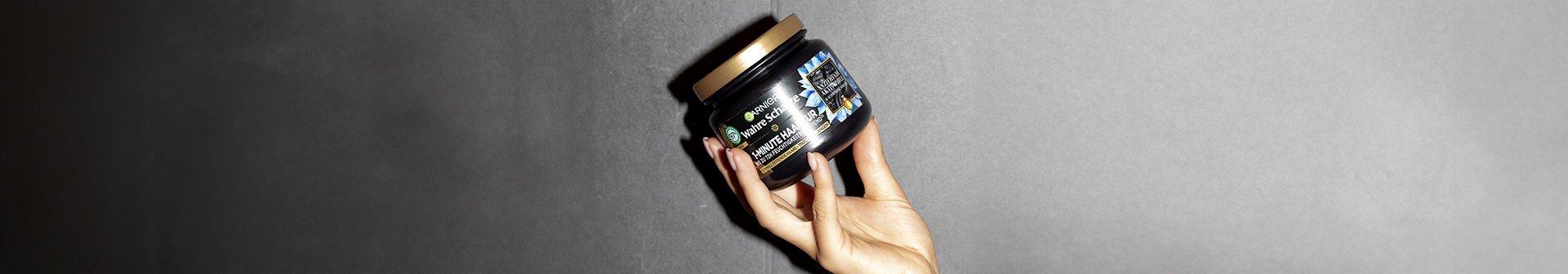 Eine Hand hält Garnier Wahre Schätze Ausgleichende Haarmaske