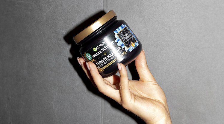 Eine Hand hält Garnier Wahre Schätze Ausgleichende Haarmaske
