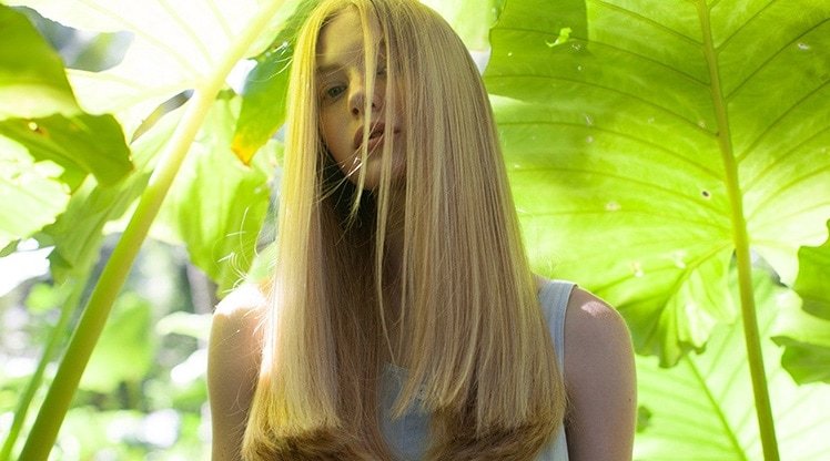 Blonde Frau vor tropischen Pflanzen