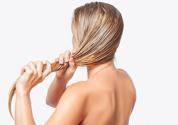 Blonde Frau mit nassem Haar dreht ihren langen, schweren Zopf