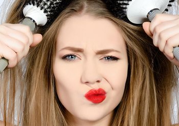 Frau fährt mit Bürsten durch trockenes Haar