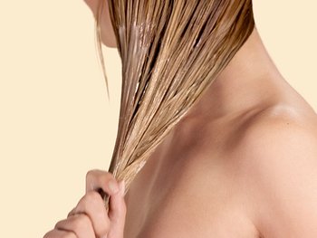 Blonde Frau, die sich Conditioner in ihr nasses Haar gibt