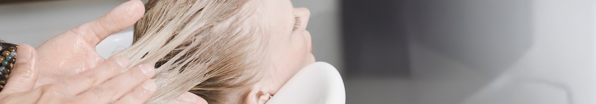 Blonde Frau, der Conditioner in ihr nasses Haar gegeben wird.