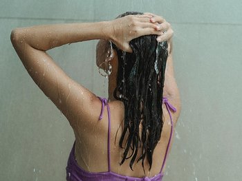 Dunkelhaarige Frau, die sich die Haare wäscht