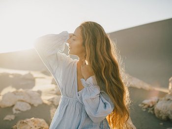 Frau mit langem blonden gepflegten Haaren an einem steinigen Strand