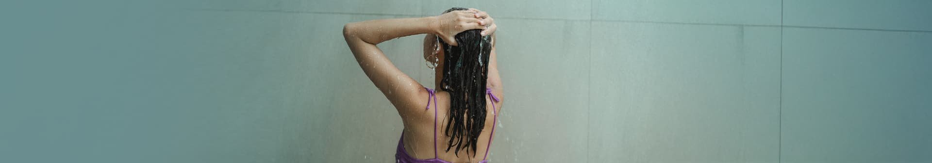 Frau wäscht ihre Haare während einer Dusche