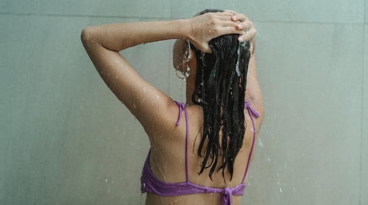 Frau wäscht ihre Haare während einer Dusche