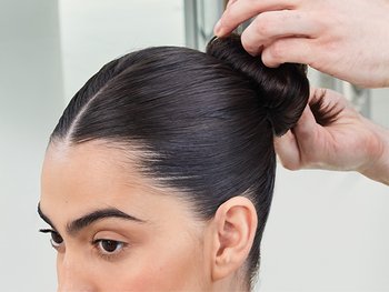 Brünette Frau bekommt einen Dutt gebunden