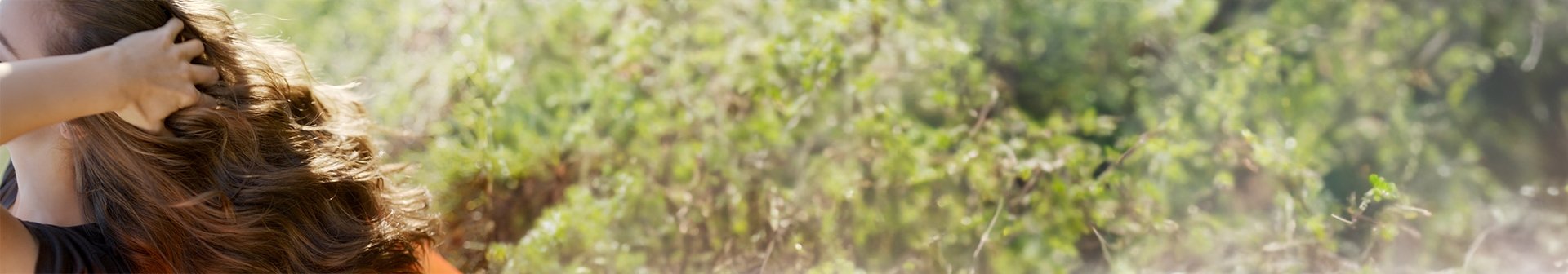 Eine Frau fasst sich in ihre langen welligen braunen Haare