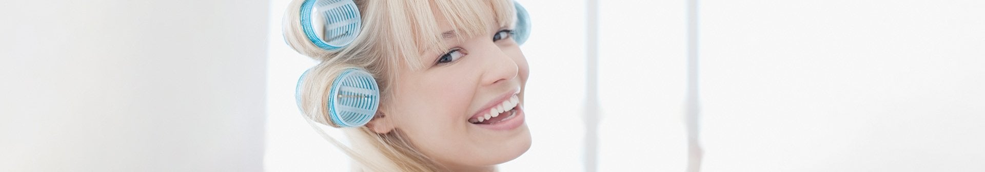 Junge Frau mit blonden Haaren mit Haarwicklern