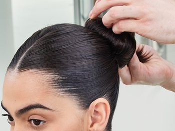 Eine Frau in Nahaufnahme, während ihr ein sleek Bun frisiert wird