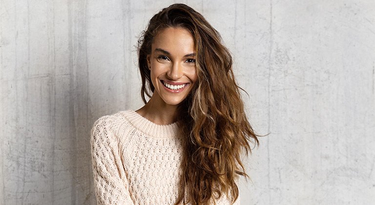 Frau mit langem, wallendem Haar lächelt in die Kamera