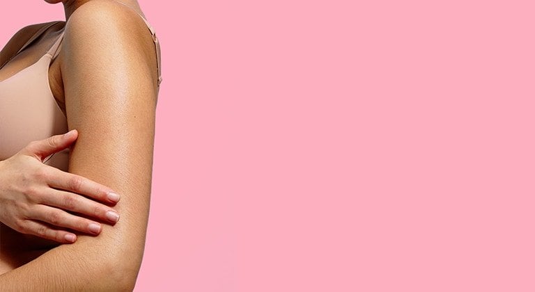 Eine Frau streicht mit der Hand über ihren Arm