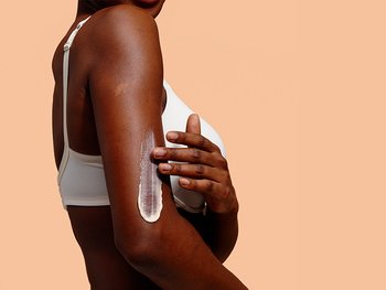 Eine Frau trägt Lotion auf ihren Arm auf