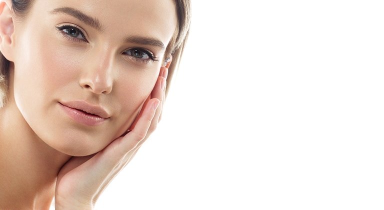 Junge Frau streicht sich über ihre linke Wange