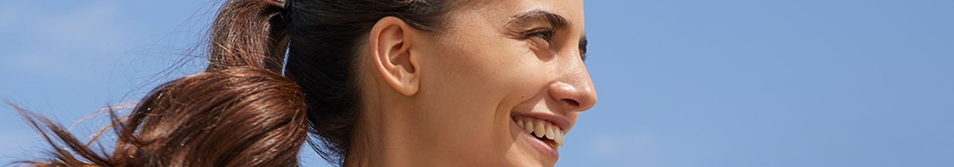 eine lächelnde junge Frau vor blauem Himmel