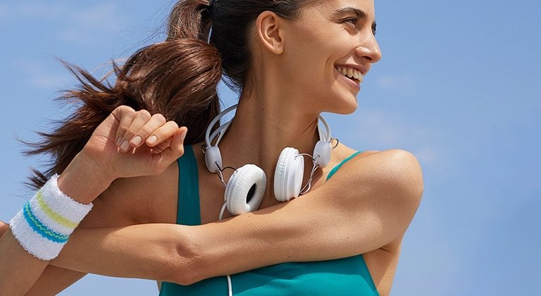 eine lächelnde sportliche junge Frau vor blauem Himmel