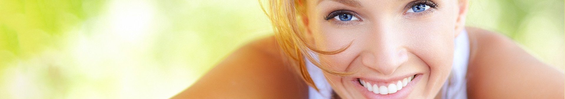 Junge Frau stützt Ihren Kopf mit dem Kinn auf ihre Hände, lächelnd