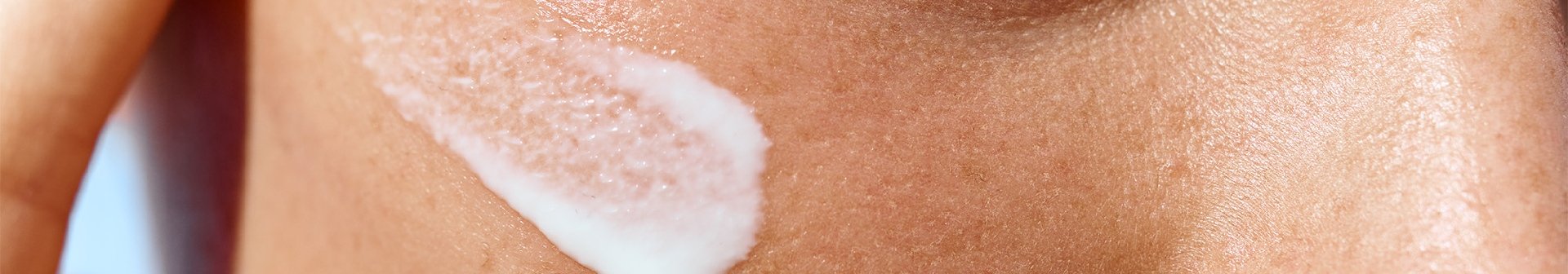 Frau trägt Sonnenschutzcreme auf ihr Gesicht auf, um sich vor Hautalterung durch Sonne zu schützen