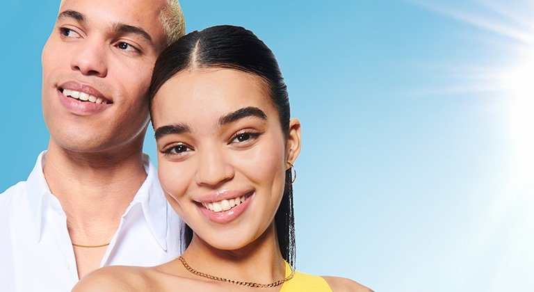 Eine junge Frau und ein junger Mann, lächelnd vor blauem Himmel