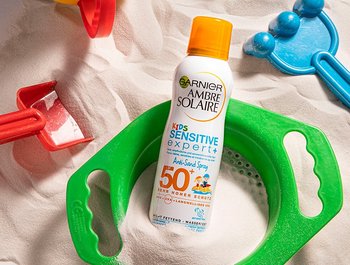 Spielzeuge im Sand und das Ambre Solaire Anti-Sand Spray LSF 50+ für Kids