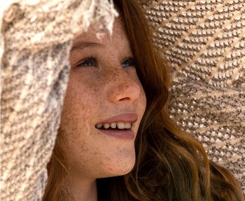 Lächelndes Kind mit Sonnenschutz über dem Kopf