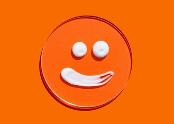 Smilygesicht aus Creme auf orangenem Hintergrund